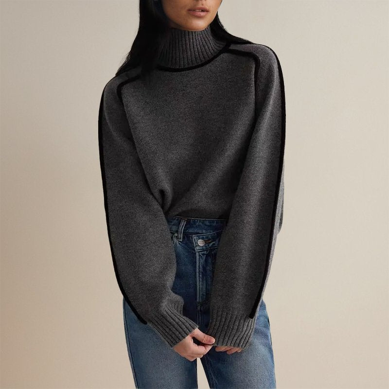 Femme portant un pull gris à col roulé et manches longues, associé à un jean bleu. Mode automne-hiver, style décontracté et élégant.