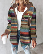 Femme portant un cardigan multicolore en tricot, style décontracté, avec un gobelet à café à la main, sur fond de mur gris. Mode automne-hiver tendance.