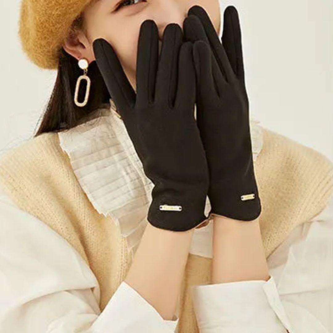 Femme portant des gants noirs élégants, béret marron et boucles d'oreilles pendantes, mode automne-hiver, style chic et moderne.