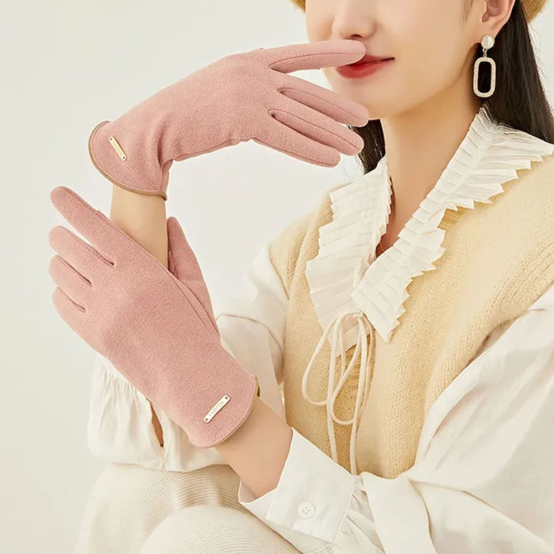 Femme portant des gants roses élégants, assise avec une tenue beige et blanche. Accessoire mode hiver, style chic et moderne.