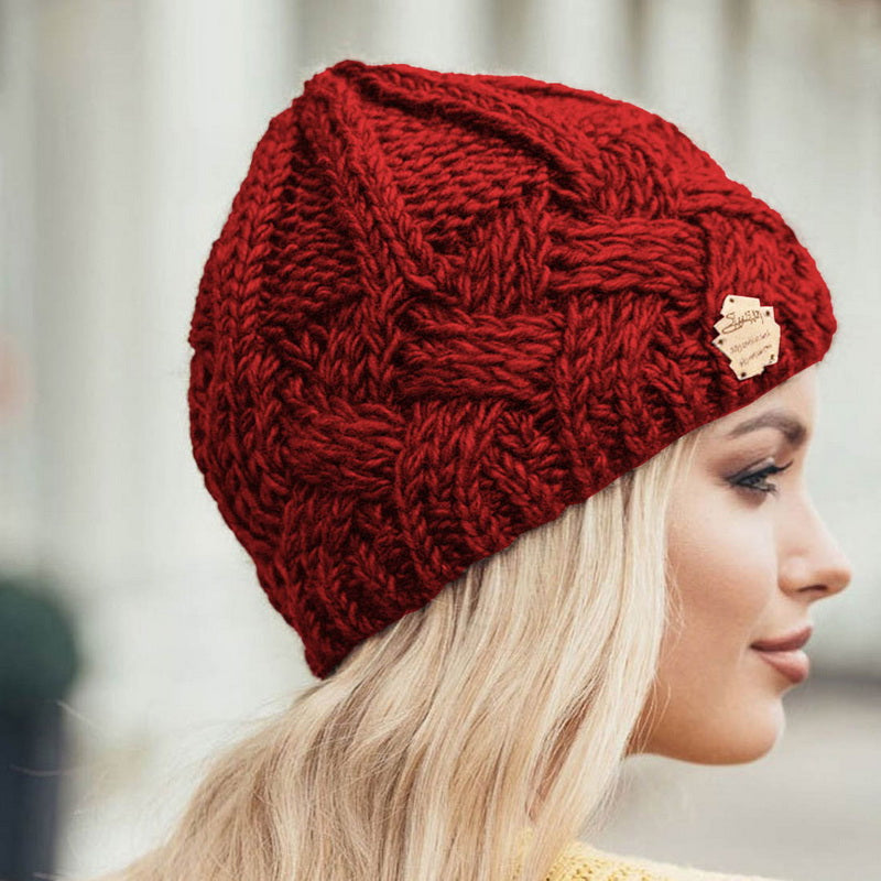Femme portant un bonnet rouge en tricot épais, style hiver, avec étiquette en cuir. Mode féminine, accessoire chaud, tendance automne-hiver.
