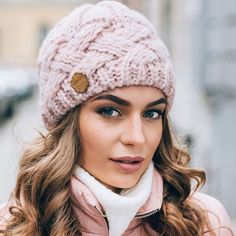 Femme portant un bonnet en laine rose tricoté, avec un motif torsadé, par temps froid. Accessoire mode hiver, style élégant et chaud.