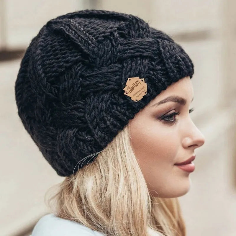 Femme portant un bonnet en laine tricoté noir avec étiquette en cuir, mode hiver, accessoire chaud, style élégant, profil extérieur.