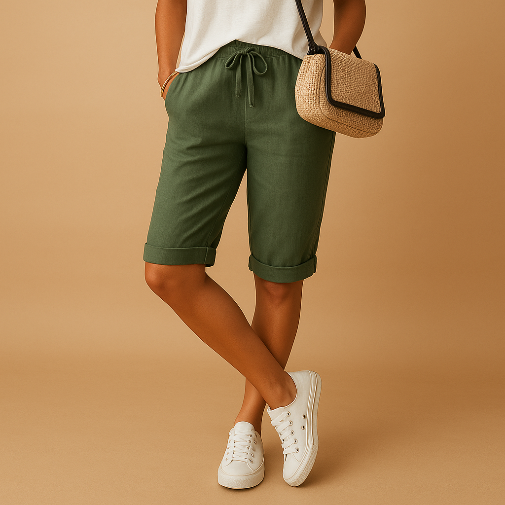 Short en lin vert pour femme, style décontracté, avec cordon de serrage. Porté avec un t-shirt blanc et des baskets blanches. Mode estivale tendance.