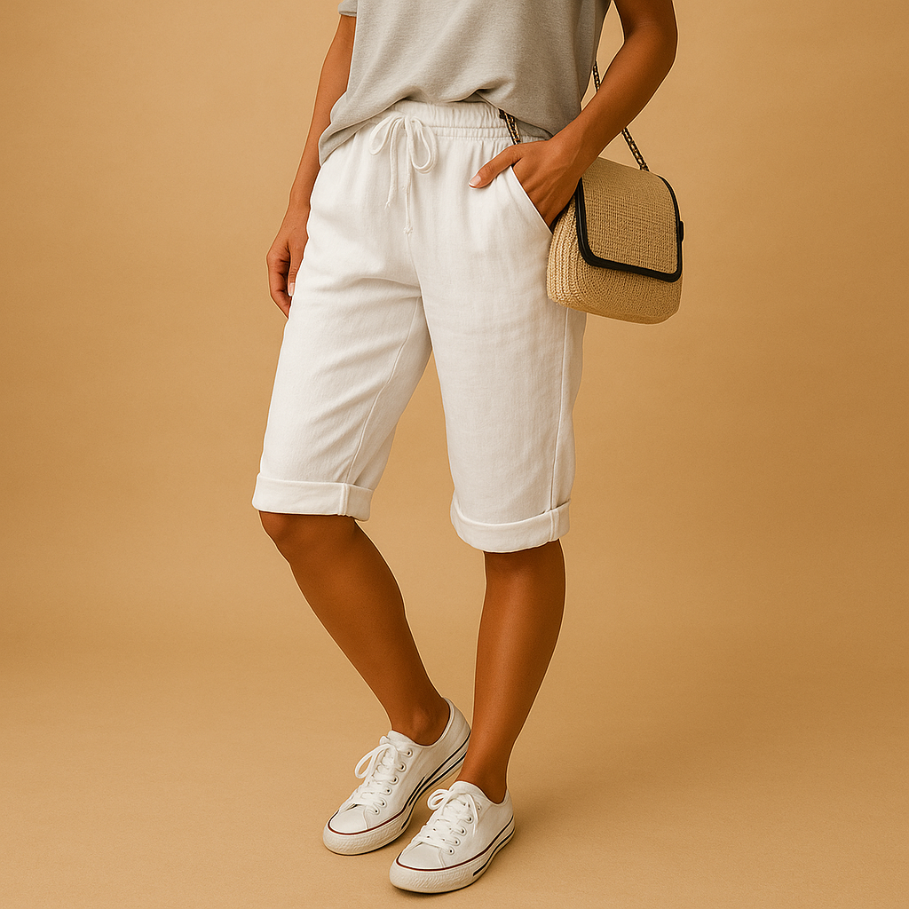 Femme portant un short blanc en lin, t-shirt gris, baskets blanches et sac en osier. Mode estivale décontractée, style chic et confortable.