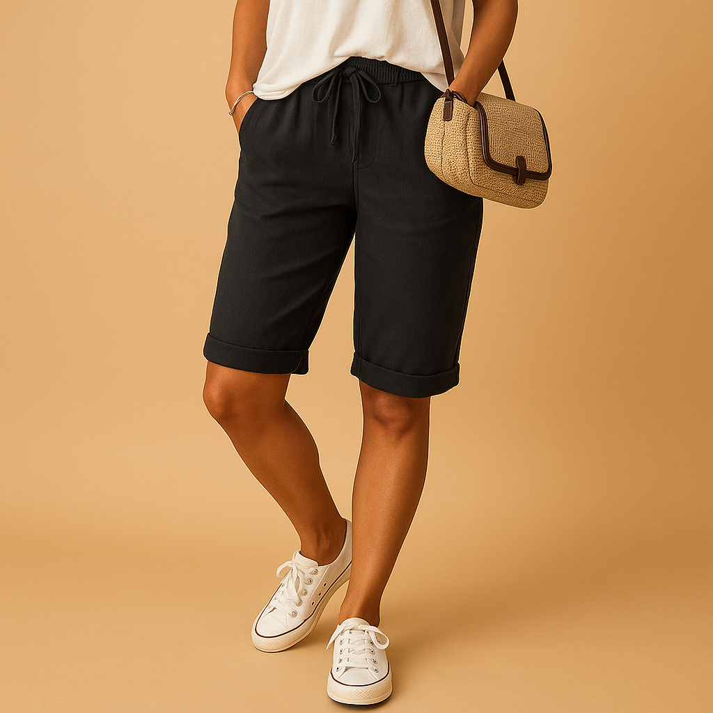 Femme portant un short noir et un t-shirt blanc, avec un sac en osier et des baskets blanches, posant sur un fond beige. Mode décontractée chic.
