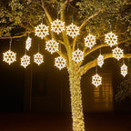 Arbre décoré de guirlandes lumineuses en forme de flocons de neige, illuminant la nuit. Décoration festive extérieure, éclairage LED.