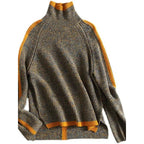 Pull-over en laine gris chiné avec col roulé, détails côtelés et rayures orange sur les manches et l'ourlet. Mode automne-hiver tendance.