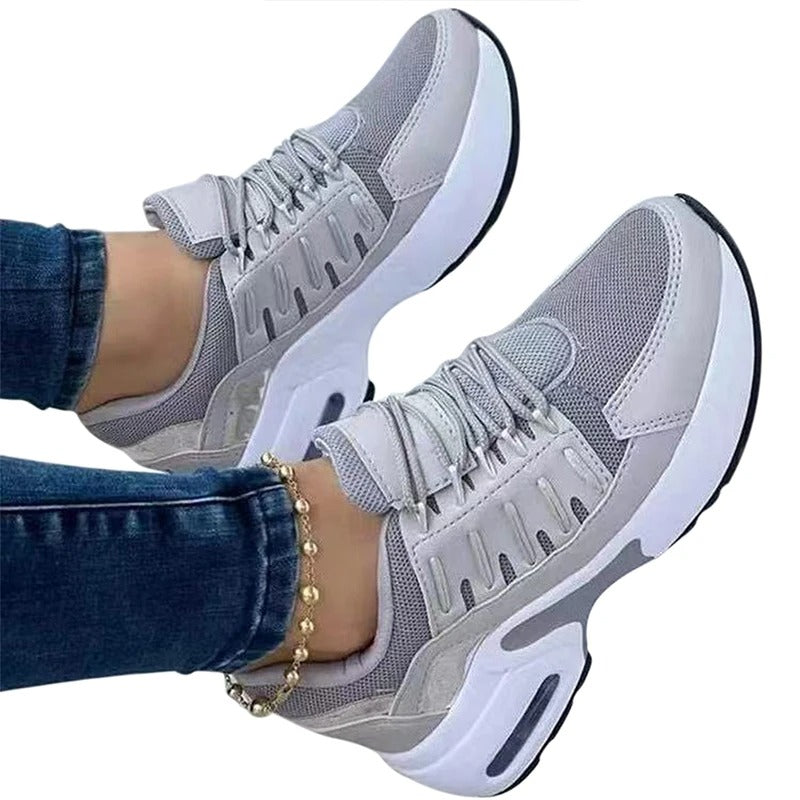 Baskets grises modernes pour femme, semelle épaisse blanche, portées avec un jean. Chaussures de sport tendance, confortables et stylées.