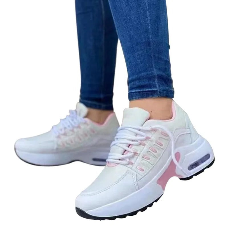 Baskets blanches et roses pour femme, semelle épaisse, portées avec un jean bleu. Chaussures de sport tendance, confortables et modernes.