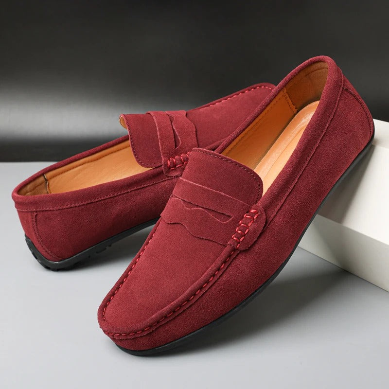 Mocassins en daim rouge pour homme, élégants et confortables, posés sur une boîte blanche. Chaussures décontractées idéales pour un style moderne.