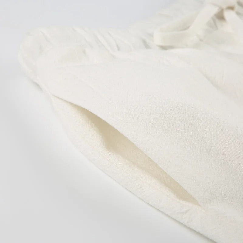 Pantalon en lin blanc cassé avec poche latérale, taille élastique et cordon. Vêtement léger et confortable pour l'été. Mode éco-responsable.
