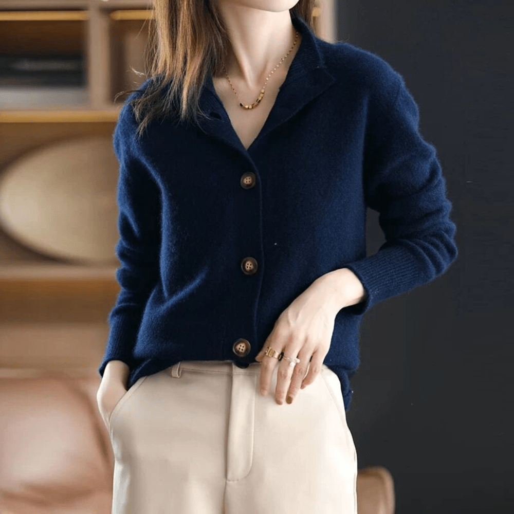 Femme portant un cardigan bleu marine en laine avec boutons, associée à un pantalon beige. Mode élégante, tenue automne-hiver, style décontracté chic.