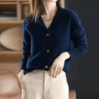 Femme portant un cardigan bleu marine en laine avec boutons, associée à un pantalon beige. Mode élégante, tenue automne-hiver, style décontracté chic.
