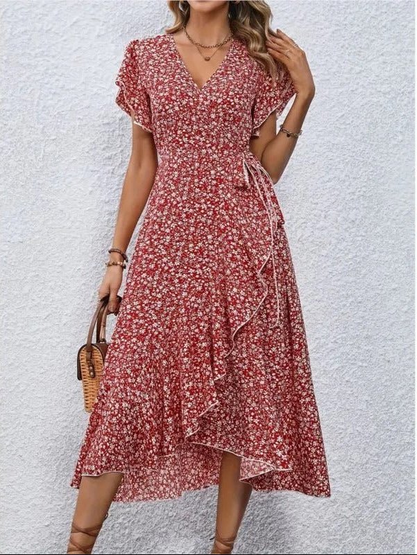 Robe longue rouge à fleurs blanches, manches courtes, col en V, portée par une femme tenant un sac en osier. Mode féminine estivale élégante.