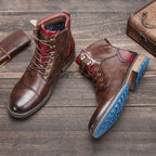 Bottes en cuir marron pour homme avec semelles bleues, posées sur un sol en bois, accompagnées d'un portefeuille et d'une valise vintage.
