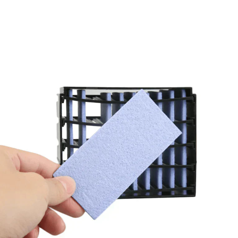 Main tenant un filtre de rechange bleu pour purificateur d'air, devant une grille noire. Accessoire essentiel pour améliorer la qualité de l'air.