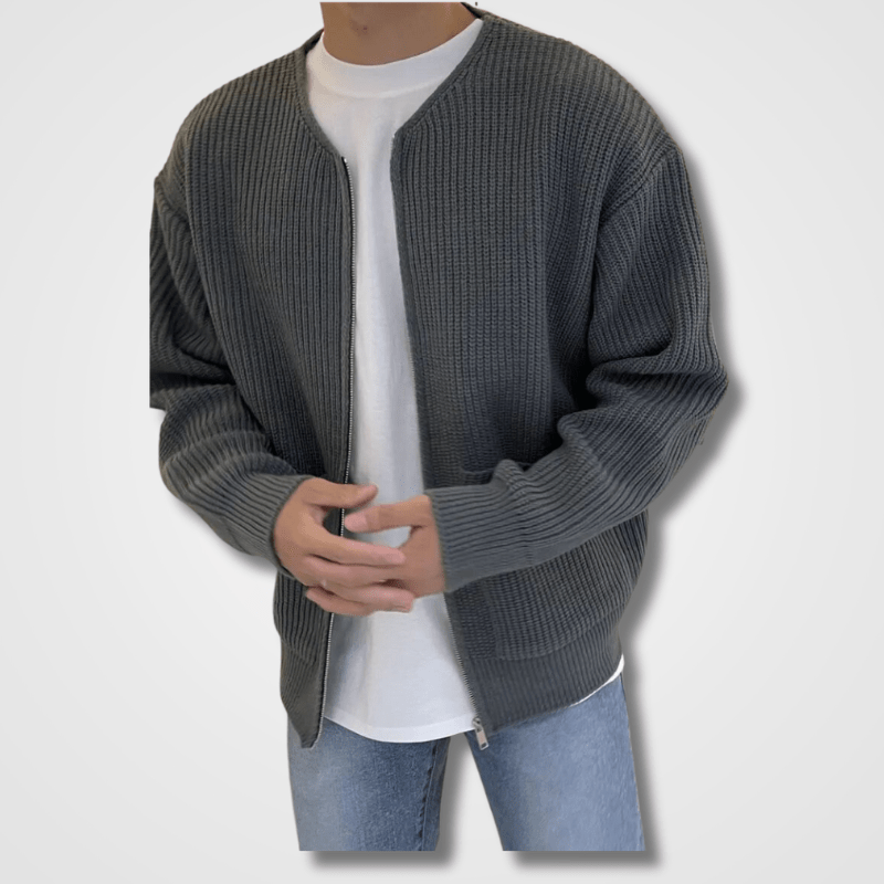Homme portant un cardigan gris en maille, t-shirt blanc et jean bleu clair. Mode décontractée, style automne-hiver, tenue moderne et élégante.