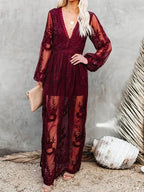 Robe longue en dentelle bordeaux avec manches longues transparentes, tenue élégante pour soirée, femme tenant une pochette beige, style bohème chic.