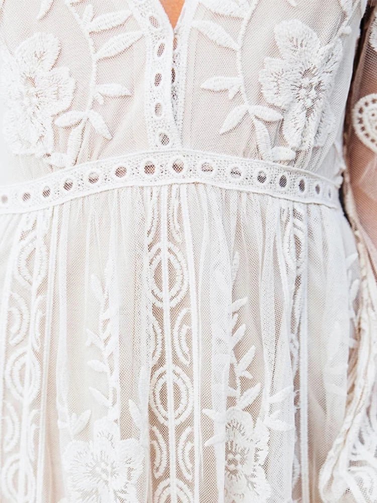 Robe en dentelle blanche avec motifs floraux délicats, manches longues, style bohème chic, idéale pour mariage ou événement spécial.
