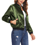 Femme portant un blouson bomber vert satiné, manches longues, avec poches, sur un t-shirt blanc et un jean déchiré. Mode tendance automne.