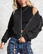 Femme portant un blouson bomber noir, top noir sans manches et jean bleu à lacets. Mode tendance, style urbain, vêtements décontractés.