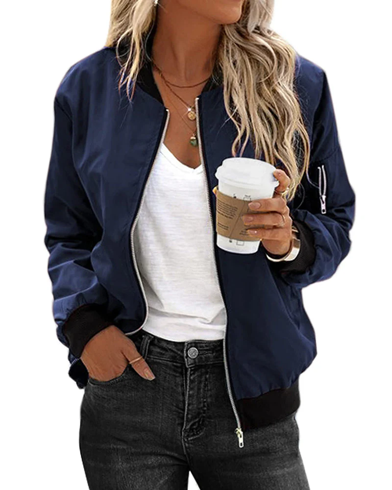 Femme portant un blouson bomber bleu marine, t-shirt blanc, jeans noir, tenant un café à emporter. Mode décontractée, style urbain tendance.