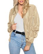 Femme portant un blouson bomber beige, t-shirt blanc et jean bleu. Mode décontractée, tendance vestimentaire, style urbain chic.