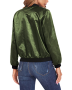 Veste bomber satinée verte pour femme, vue de dos, manches longues, col et poignets noirs, portée avec un jean bleu ajusté.