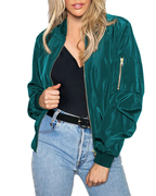 Femme portant un blouson bomber vert émeraude, t-shirt noir et jean bleu clair. Mode féminine, style décontracté, tendance vestimentaire.