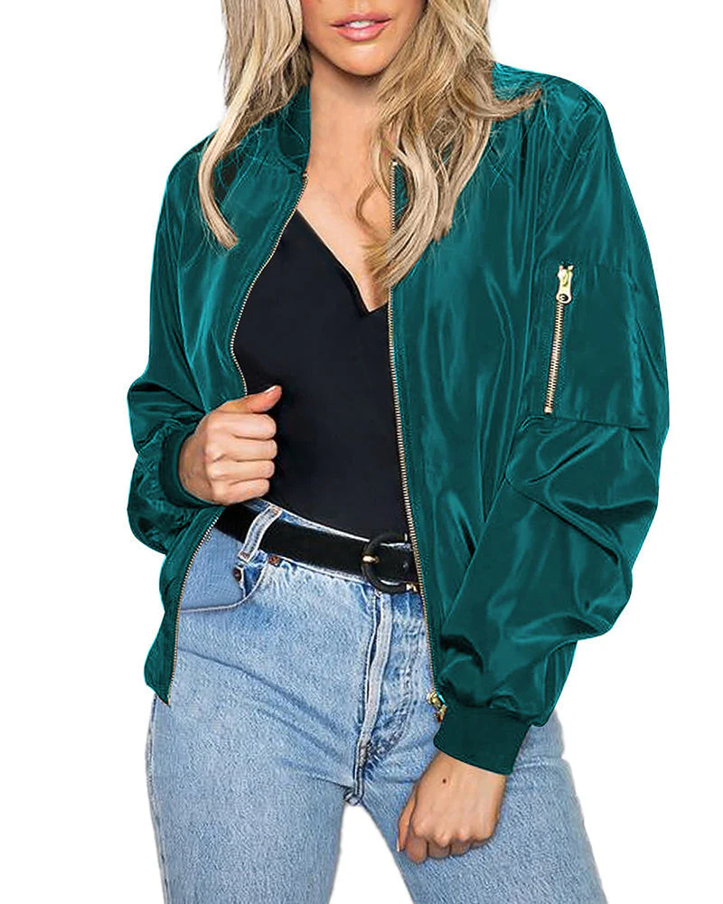 Femme portant un blouson bomber vert émeraude, t-shirt noir et jean bleu clair. Mode féminine, style décontracté, tendance vestimentaire.