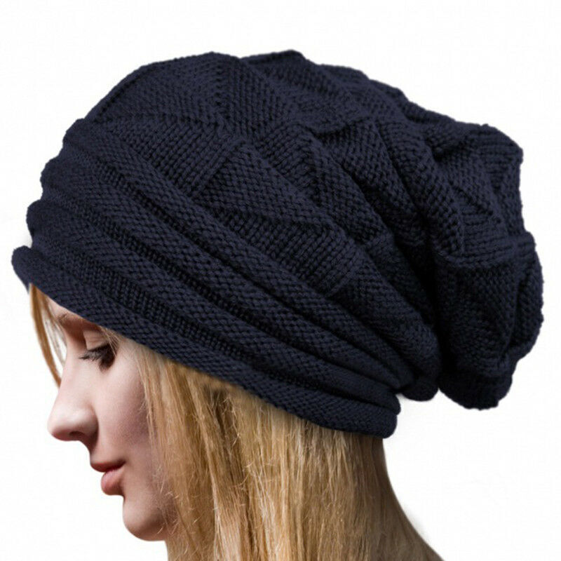 Femme portant un bonnet en tricot noir, style slouchy, sur fond blanc. Accessoire de mode hiver, tendance et confortable.