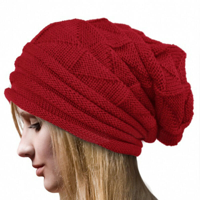 Femme portant un bonnet rouge en tricot, style slouchy, sur fond blanc. Accessoire de mode hiver, tendance et confortable.