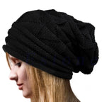 Femme portant un bonnet en tricot noir, style slouchy, cheveux blonds visibles. Accessoire de mode hiver, tendance et confortable.