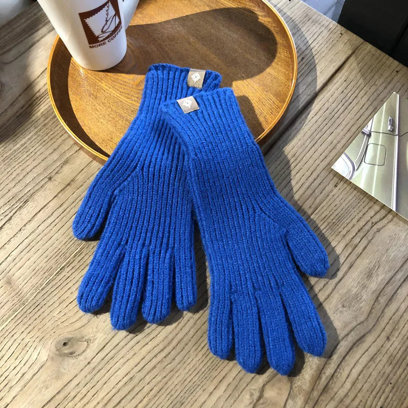 Gants en laine bleue sur une table en bois, à côté d'une tasse de café et d'un plateau. Accessoires d'hiver élégants et confortables.