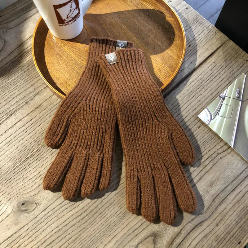 Gants en laine marron sur une table en bois, accompagnés d'une tasse de café et d'un plateau rond. Accessoire d'hiver élégant et chaud.