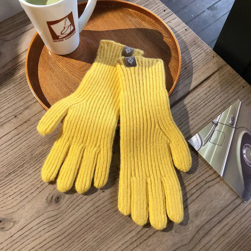 Gants en laine jaune vif sur une table en bois, à côté d'une tasse de café et d'une carte postale. Accessoire d'hiver chaud et élégant.