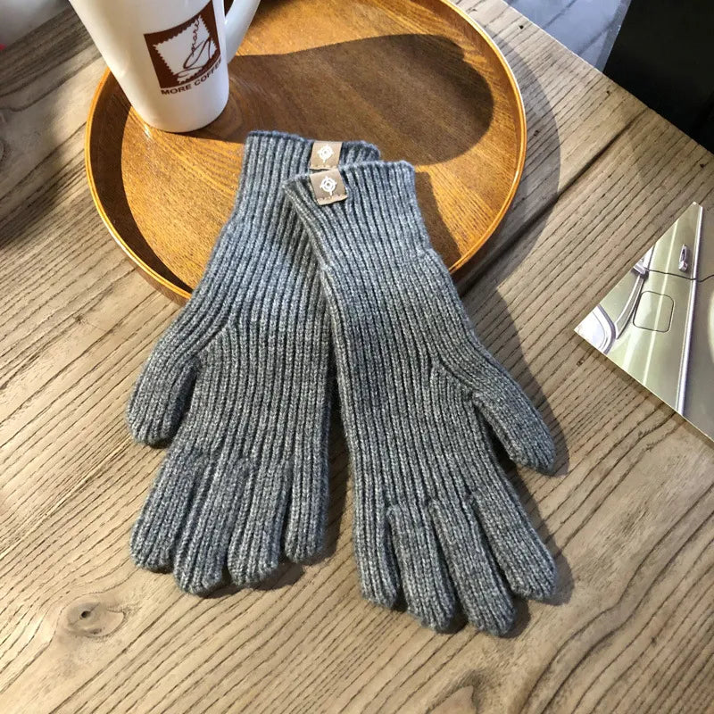 Gants en laine gris sur une table en bois, à côté d'une tasse de café et d'un plateau. Accessoire d'hiver élégant et chaud.