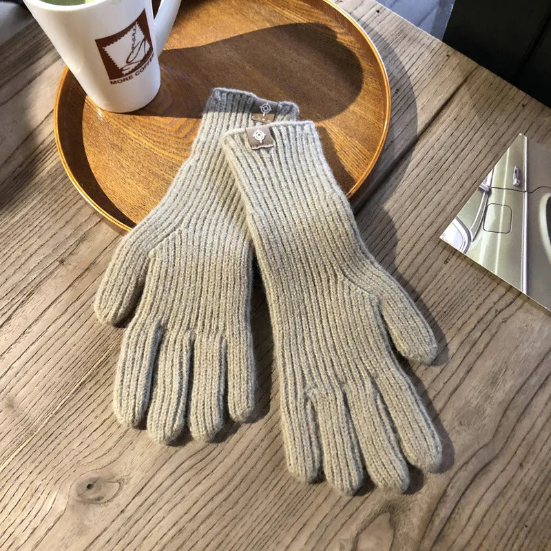 Gants en laine beige sur une table en bois, accompagnés d'une tasse de café et d'un plateau en bois. Accessoires d'hiver élégants et confortables.