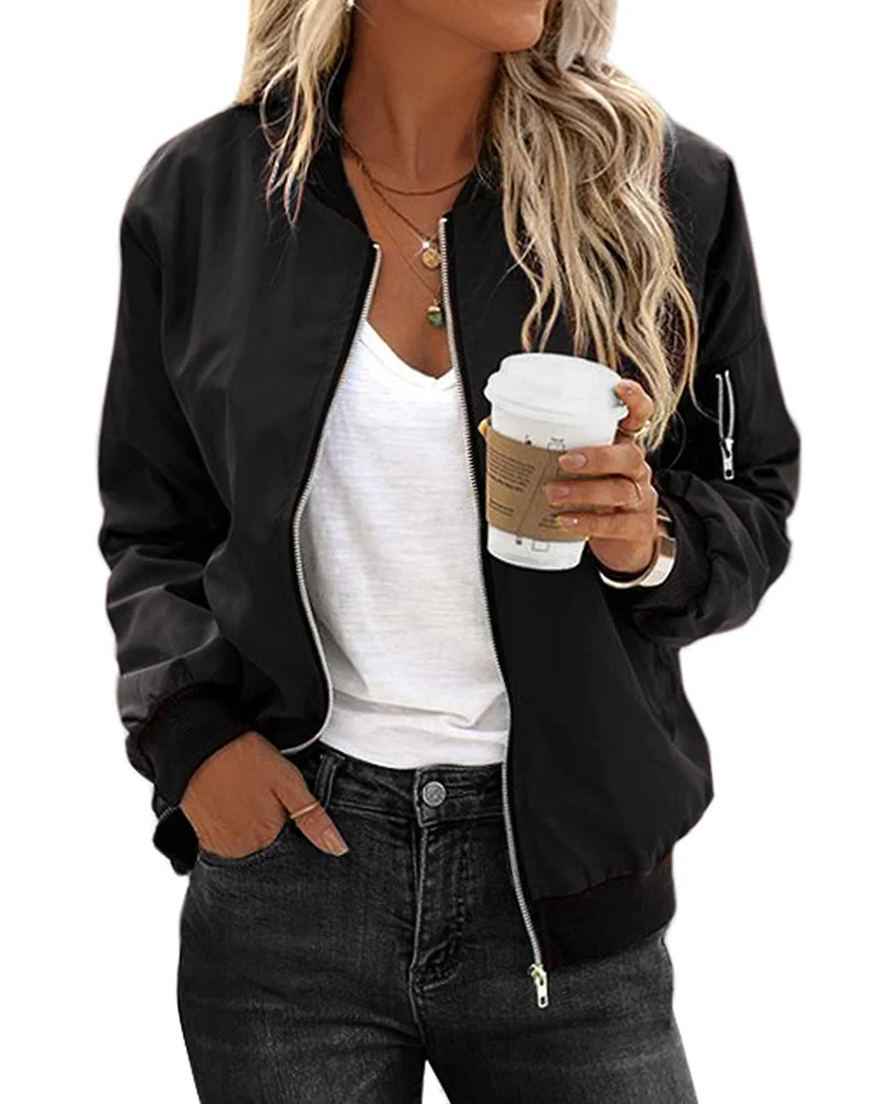 Femme en veste noire, t-shirt blanc, tenant un gobelet de café. Mode décontractée, style urbain, cheveux blonds ondulés.