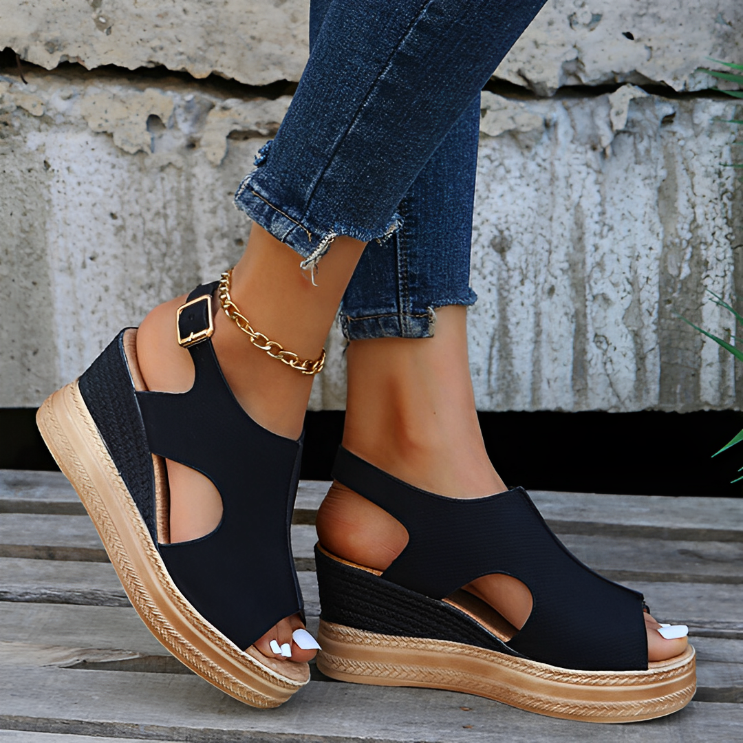 Sandales compensées noires élégantes avec semelle en corde, portées avec un jean décontracté. Chaussures d'été tendance pour femmes.