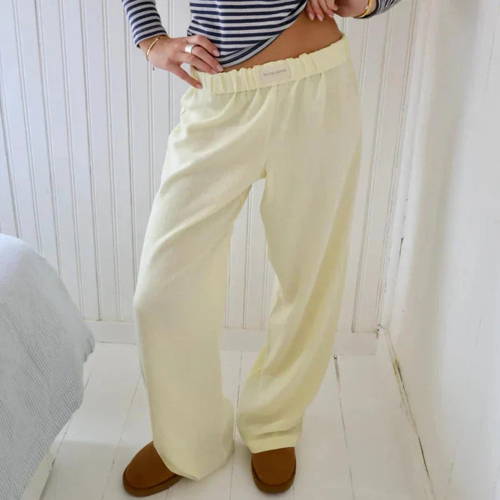 Pantalon de pyjama jaune clair pour femme, taille élastique, porté avec un haut rayé bleu et blanc, confort et style décontracté à la maison.