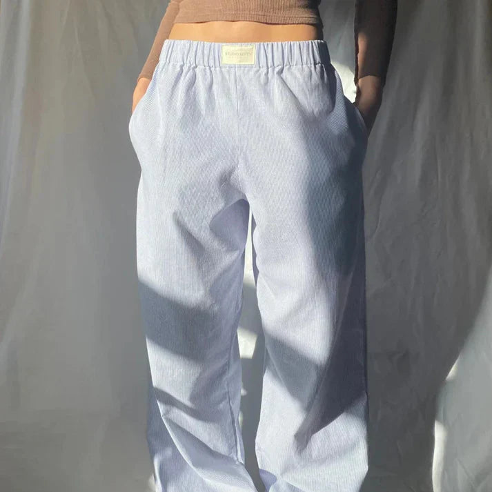 Pantalon ample à rayures bleues et blanches, style décontracté, poches latérales, porté par une personne en haut marron. Mode tendance confortable.