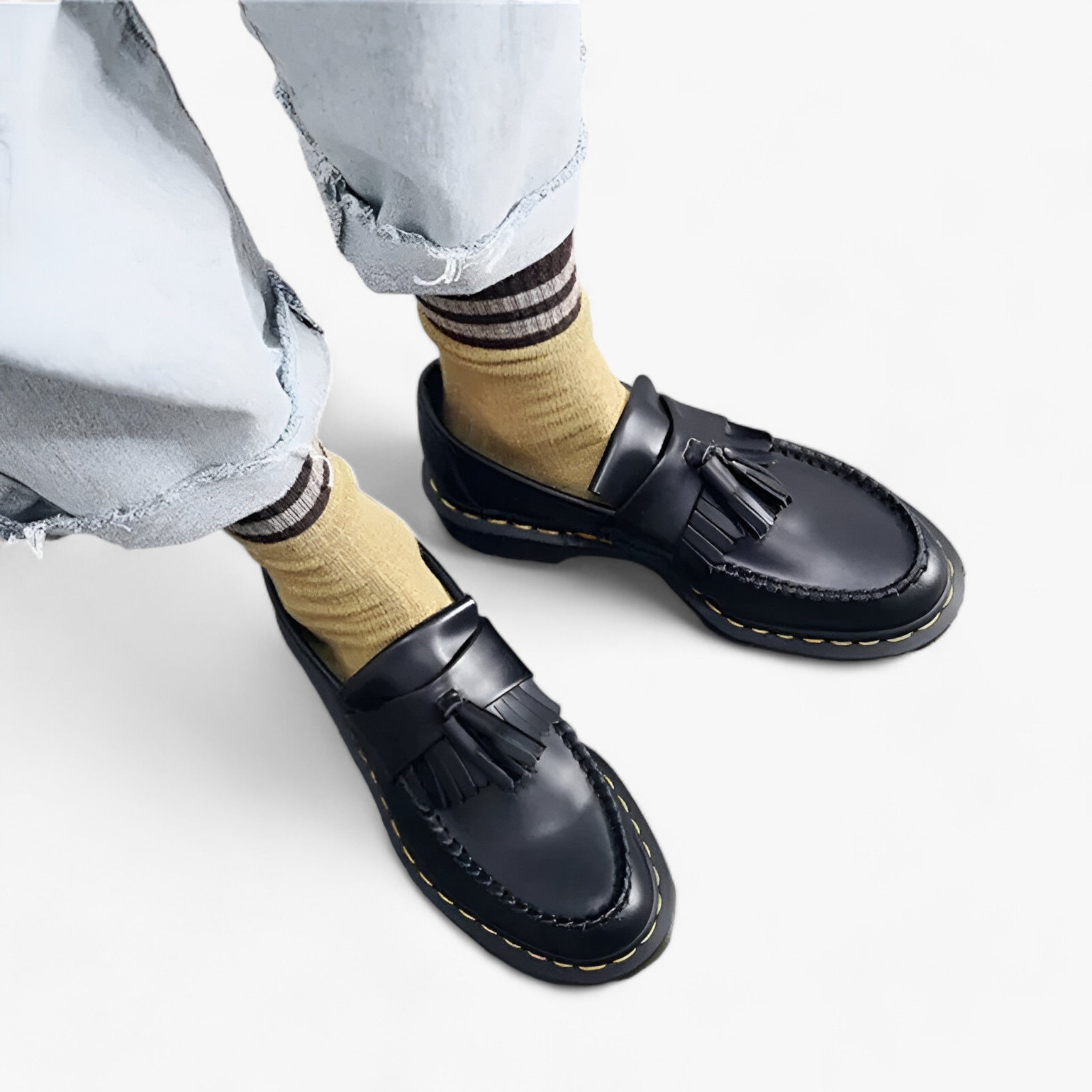 Chaussures mocassins en cuir noir avec pampilles, portées avec des chaussettes jaunes et un jean décontracté. Mode tendance, style urbain.