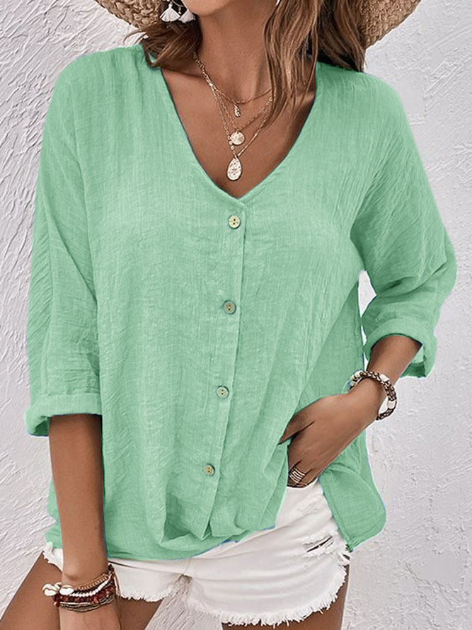 Femme portant une chemise verte en lin à manches longues, boutons en bois, associée à un short blanc. Style décontracté estival, mode féminine tendance.