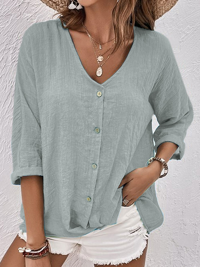 Femme portant une chemise en lin vert clair à manches longues et boutons, associée à un short blanc. Style décontracté estival, mode féminine tendance.