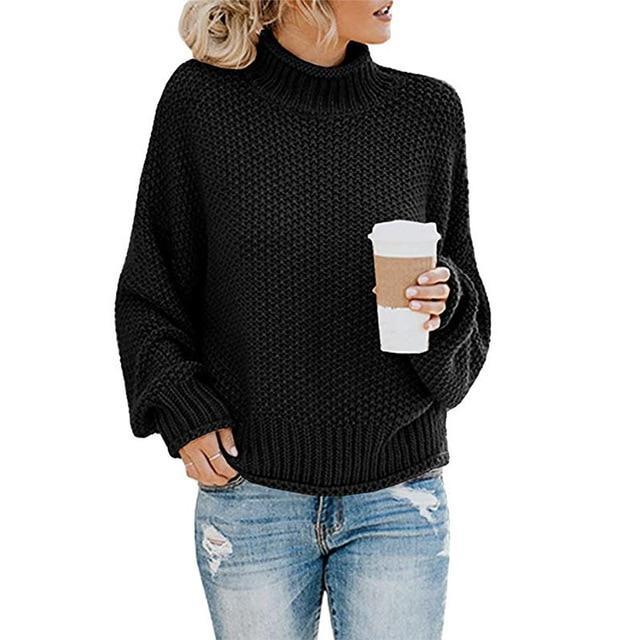 Femme portant un pull noir en tricot avec un col roulé, tenant un gobelet de café, vêtue d'un jean déchiré. Mode automne-hiver, style décontracté.
