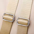 Boucles métalliques argentées sur sangles en nylon beige, gros plan. Accessoires de mode, ceinture réglable, design élégant et moderne.