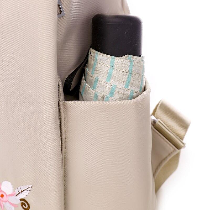 Sac à dos beige avec poche latérale contenant un parapluie rayé bleu et blanc et une bouteille noire. Accessoire pratique et élégant.