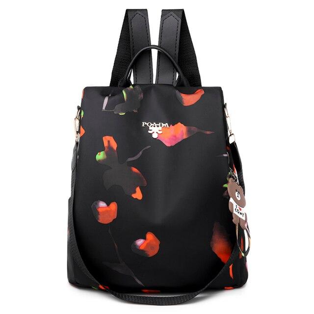 Sac à dos noir élégant avec motifs floraux colorés, bretelles ajustables, et porte-clés ours. Idéal pour mode urbaine et usage quotidien.